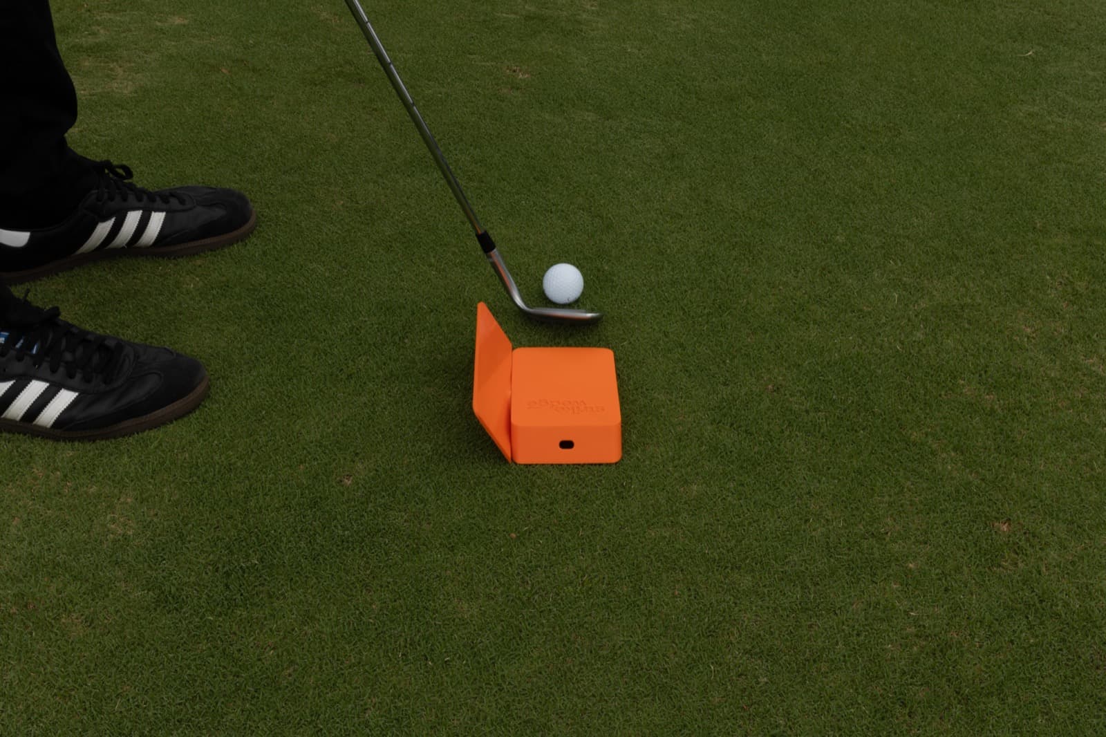 Golfer addressing a ball with the orange Strike Wedge feedback walls framing the swing